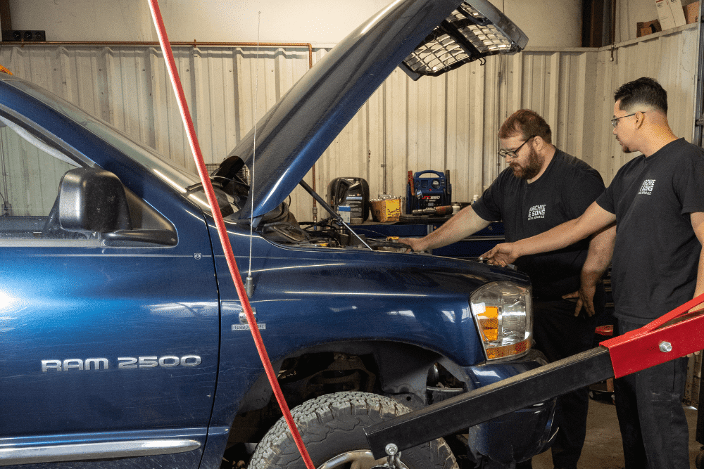 truck maintenance, diesel repair in Dudley, NC at Archie & Sons Diesel Repair. Mechanics inside an auto repair shop inspecting a RAM 2500 with the hood open.