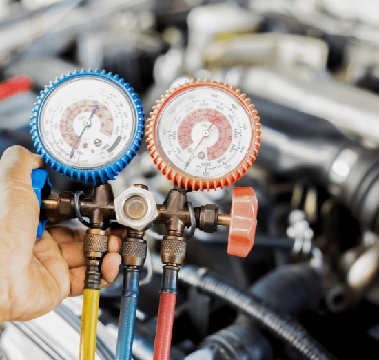 diesel truck a/c repair, diesel repair in Dudley, NC at Archie & Sons Diesel Repair. A close-up of a technician using a manifold gauge set to check refrigerant pressure in a vehicle's air conditioning system.