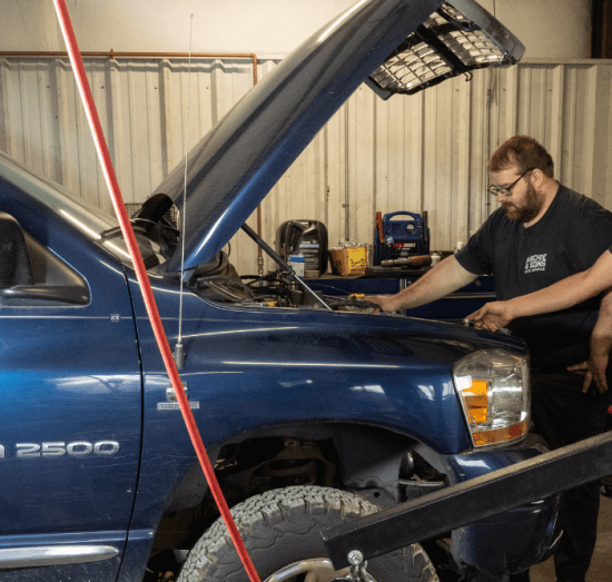 truck maintenance, diesel repair in Dudley, NC at Archie & Sons Diesel Repair. Mechanics inside an auto repair shop inspecting a RAM 2500 with the hood open.